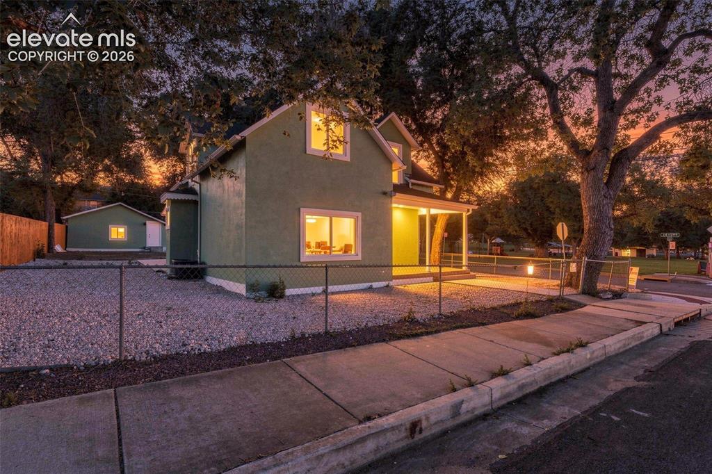 Image 5 of 50: Stucco exterior with white trim, covered front porch, gravel landscaping, a