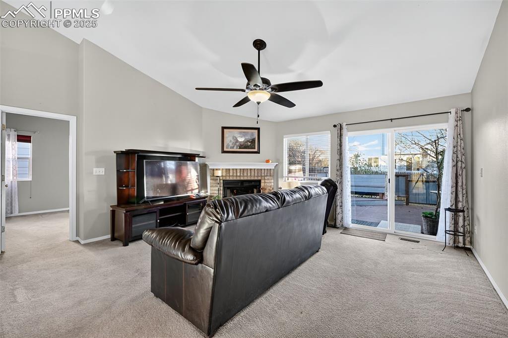 Image 10 of 41: Living area with vaulted ceiling, light carpet, a brick fireplace with Elec
