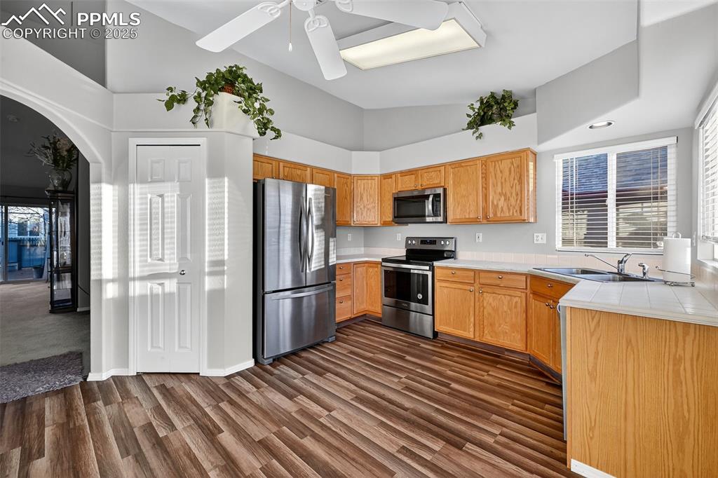 Image 13 of 41: Kitchen with stainless steel appliances, vaulted ceiling, dark wood-type fl