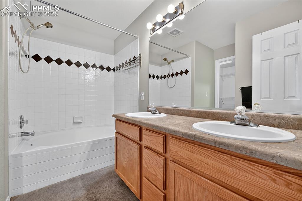 Image 20 of 41: Bathroom featuring double vanity, tiled shower / bath combo.