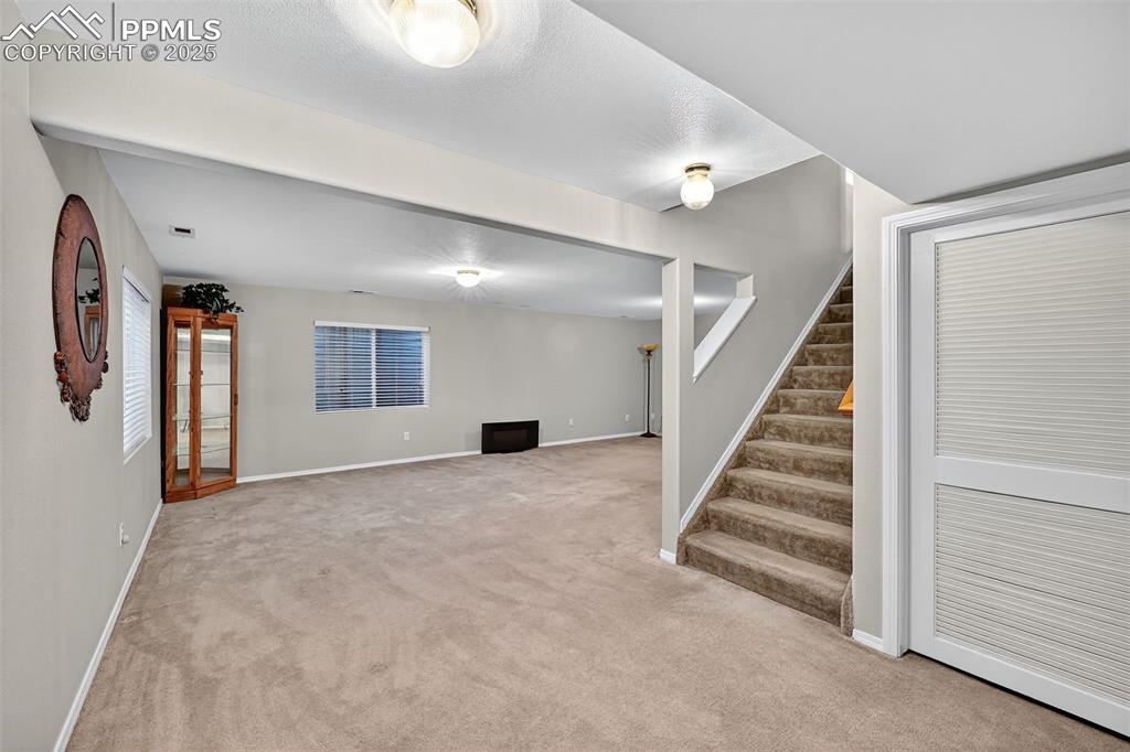 Image 25 of 41: Spacious Basement featuring light colored carpet and stairway