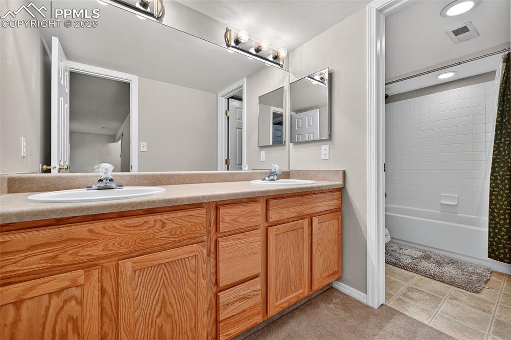 Image 32 of 41: Lower Level Bathroom with double vanity, shower / tub combo with curtain, a