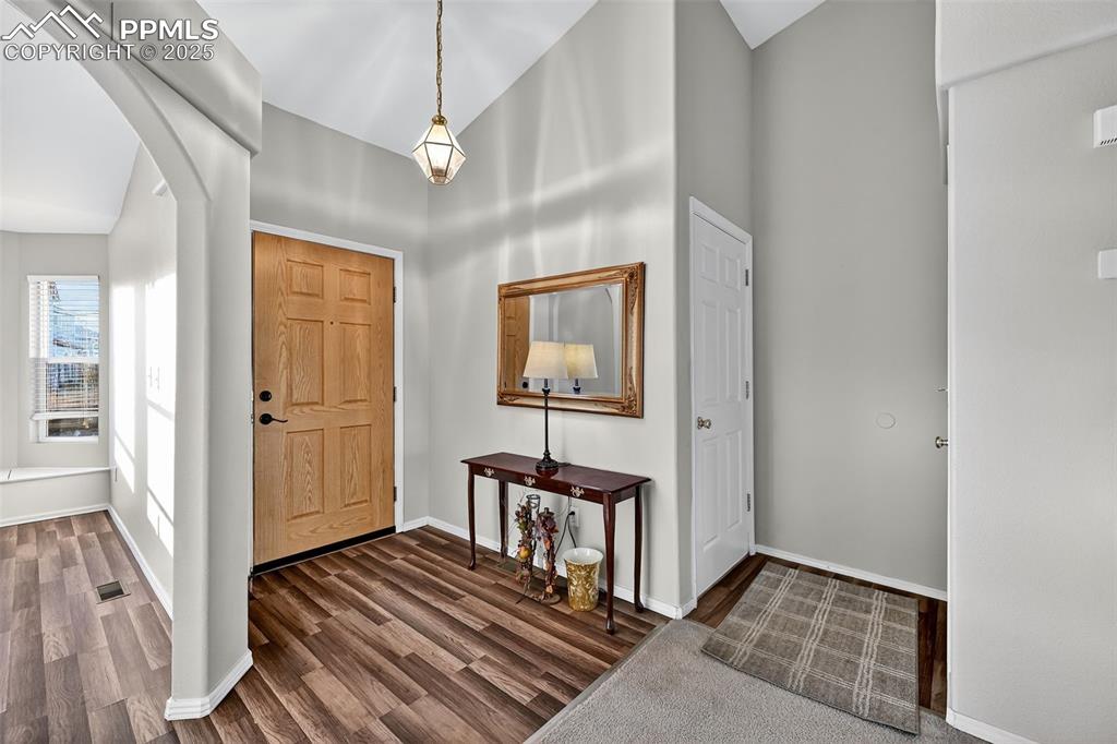 Image 7 of 41: Entrance foyer featuring arched walkways and dark wood pergo-style flooring