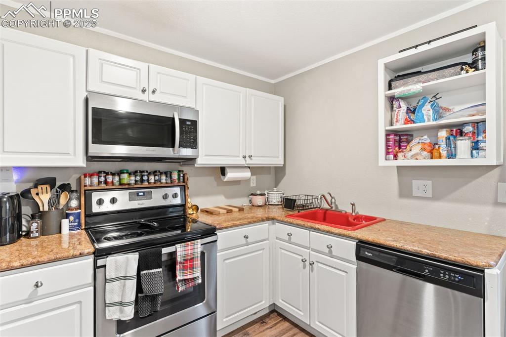 Image 10 of 26: Kitchen with stainless steel appliances, white cabinets, crown molding, ope
