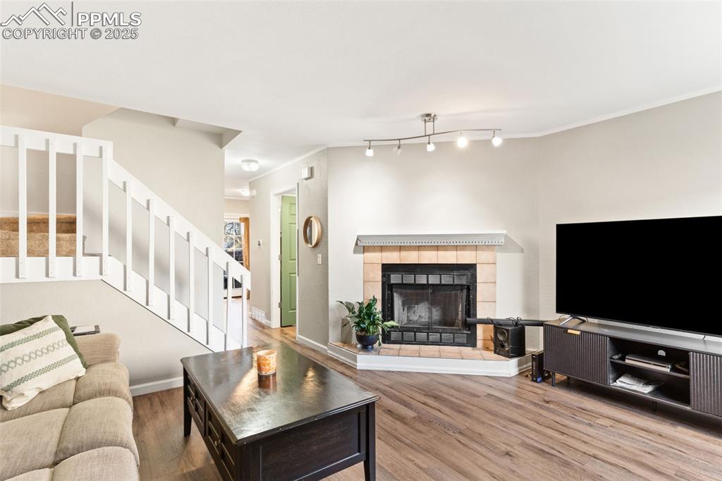 Image 5 of 26: Living room featuring stairway, a tiled fireplace, wood finished floors, an