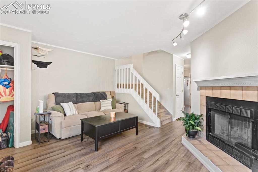 Image 6 of 26: Living area featuring stairway, wood finished floors, and a tiled fireplace