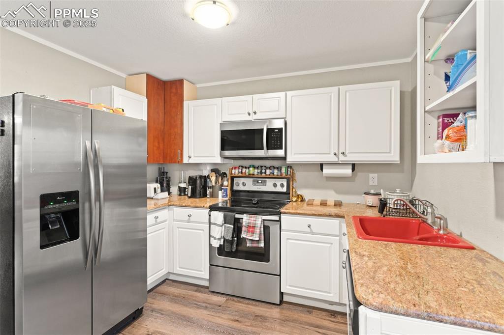 Image 8 of 26: Kitchen featuring appliances with stainless steel finishes, white cabinetry