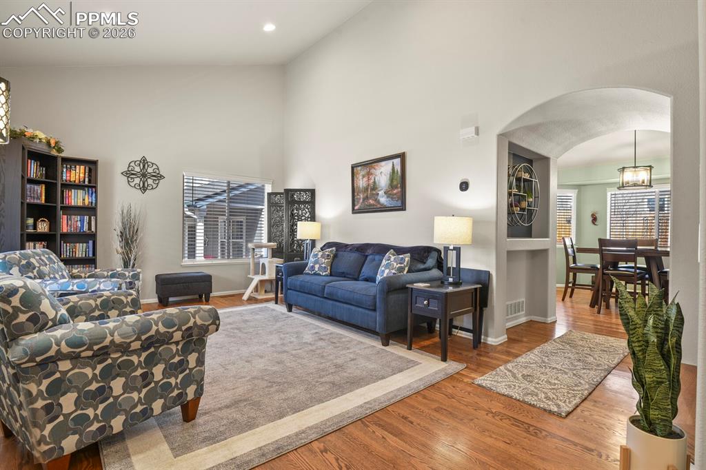 Image 8 of 43: The front living room with beautiful hardwood flooring and an arched entry 
