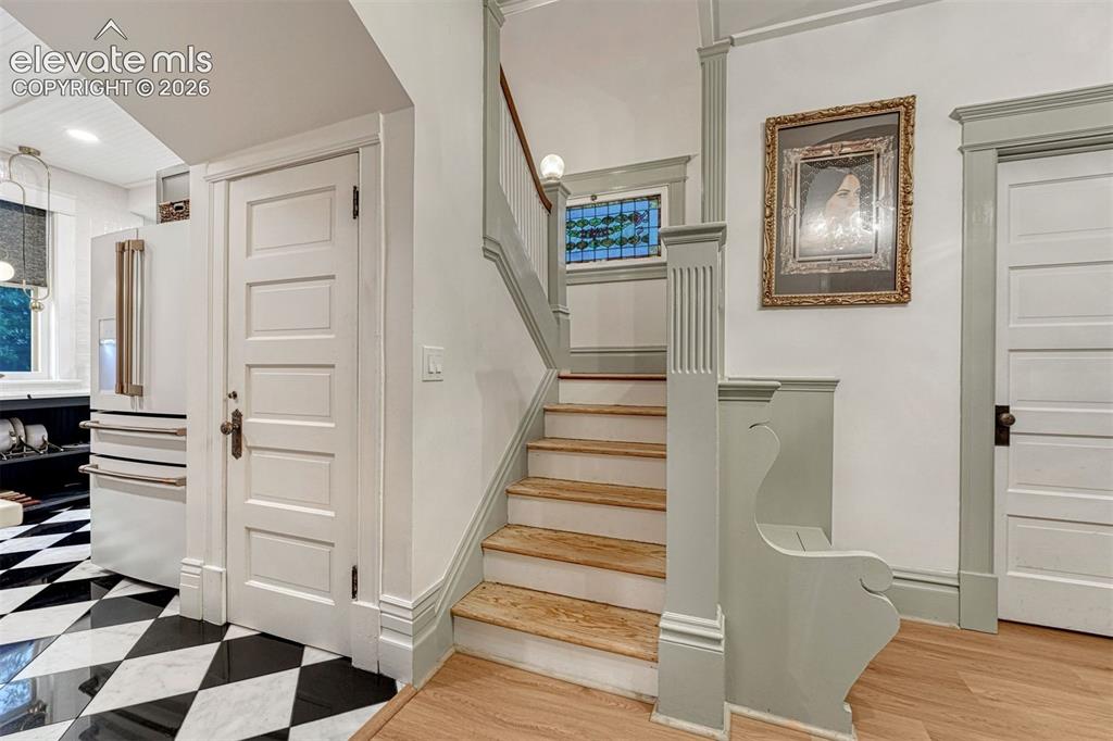Image 14 of 50: Staircase with wood treads and painted railing, featuring a stained glass w