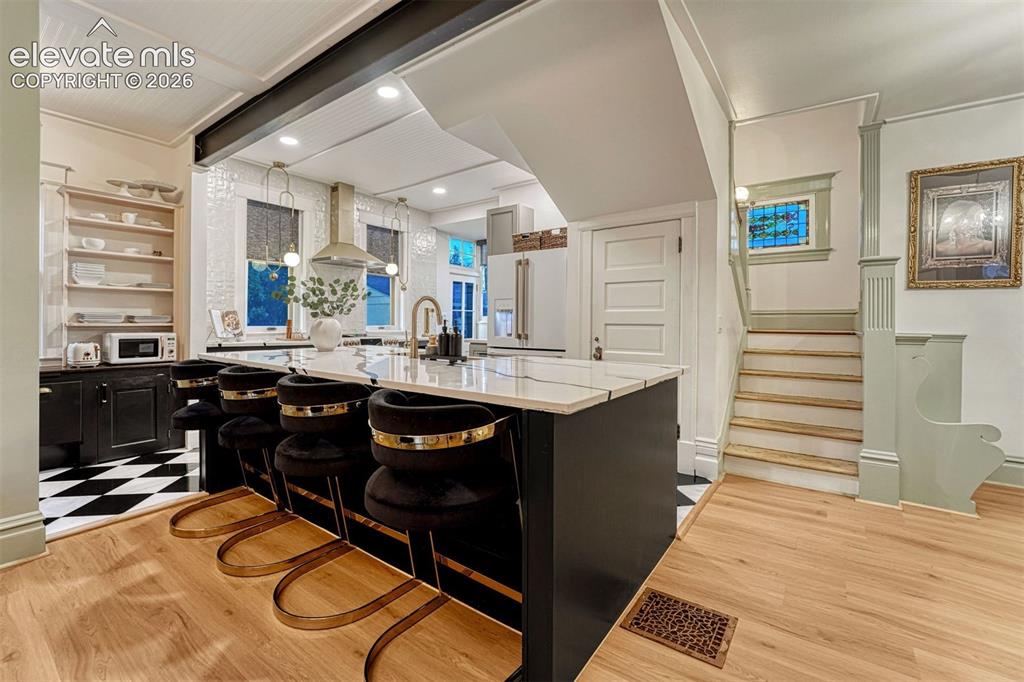 Image 21 of 50: Kitchen island with seating, wood-finish flooring, white subway tile backsp