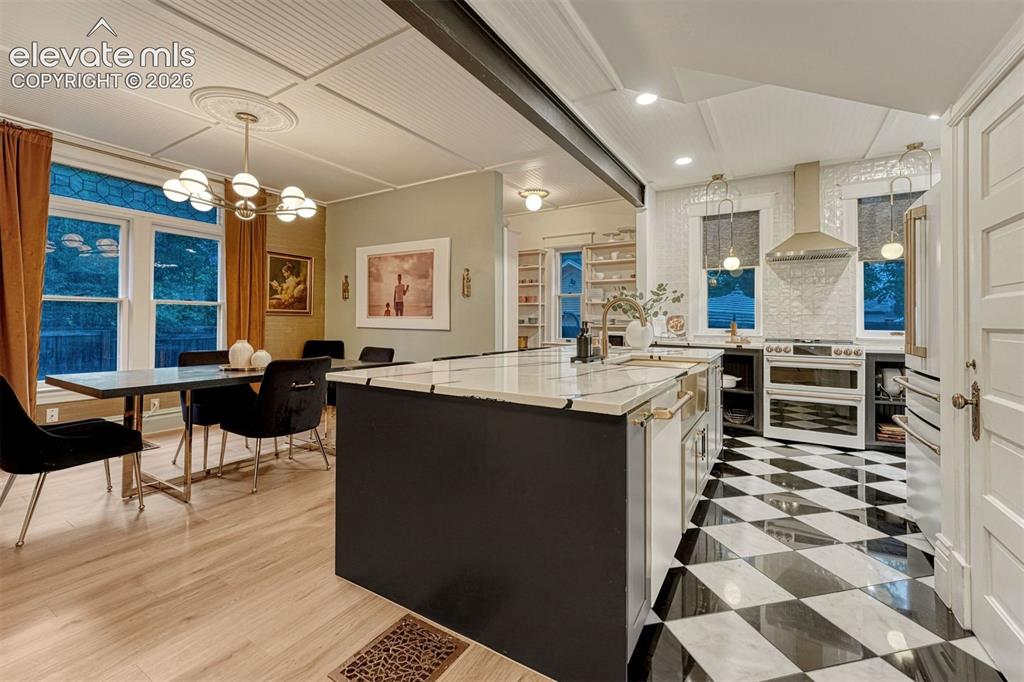 Image 22 of 50: Kitchen featuring a large island with white stone countertop, checkered flo