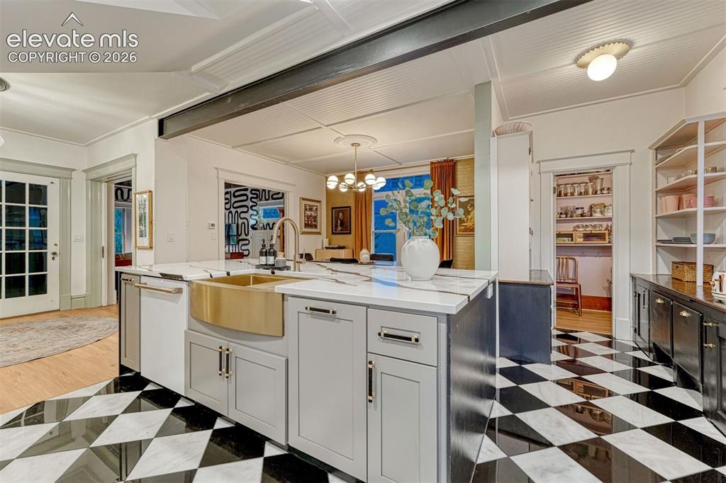 Image 25 of 50: Kitchen featuring a large island with a brass farmhouse sink, light gray ca