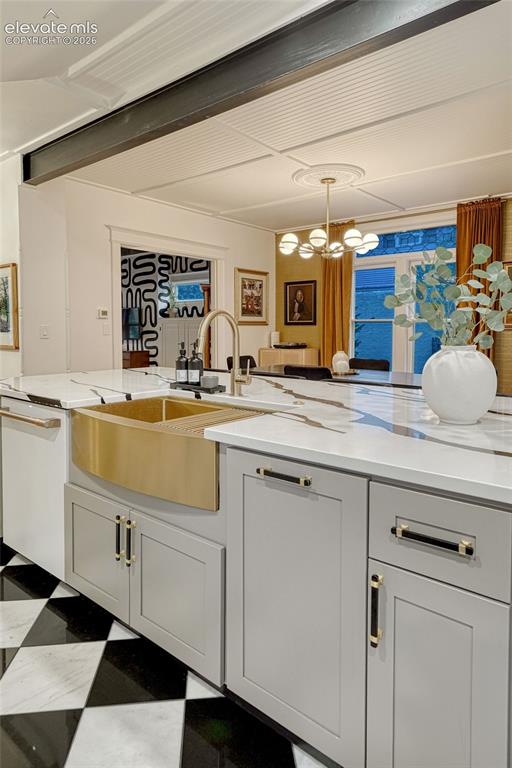 Image 26 of 50: White countertop with dark veining, gold-tone farmhouse sink, matte black a