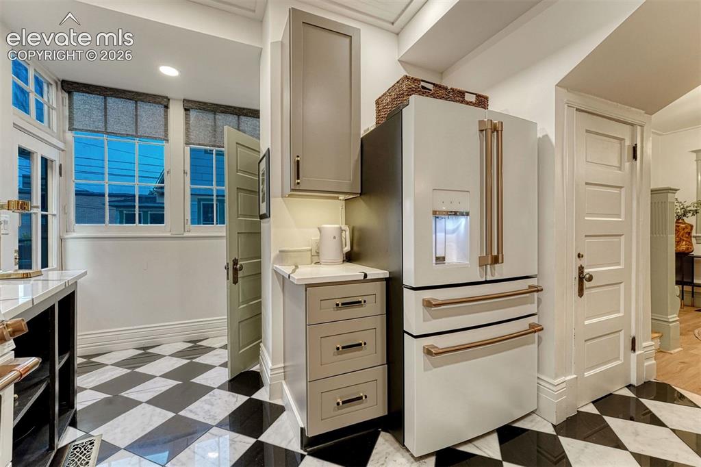Image 28 of 50: Black and white checkerboard tile flooring, white paneled doors, built-in c