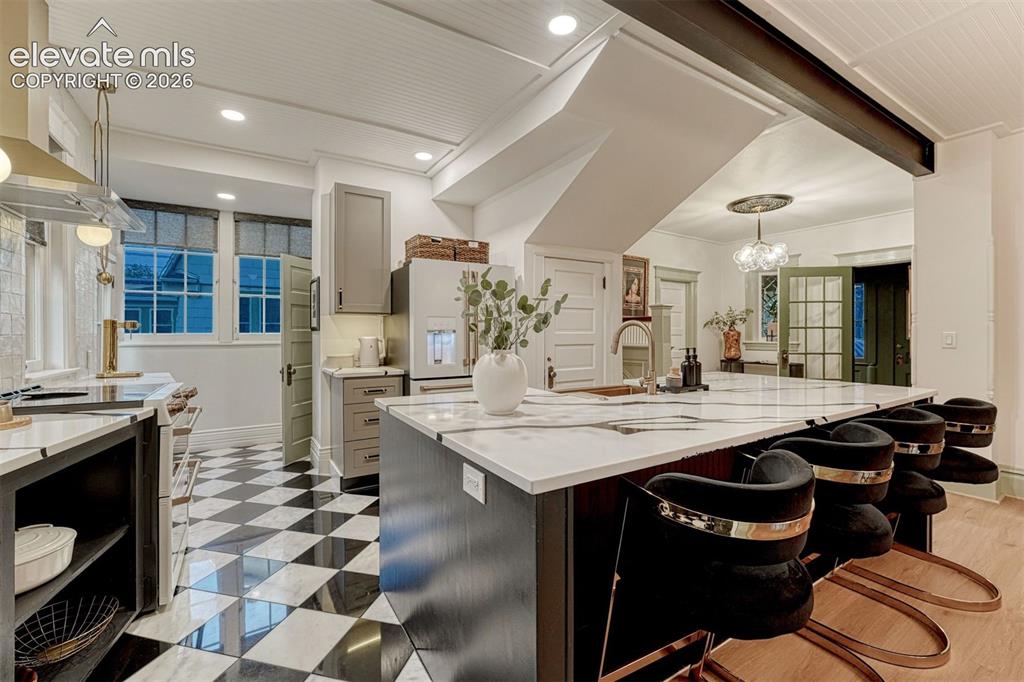 Image 29 of 50: Kitchen featuring an expansive island with a marble-finish countertop, chec