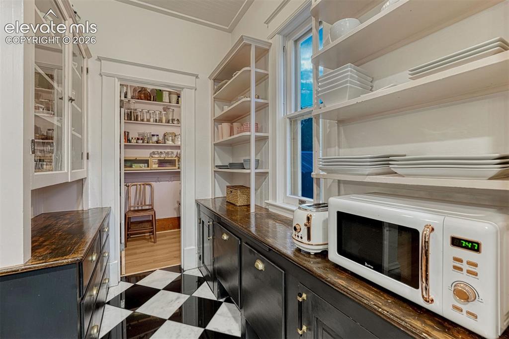 Image 30 of 50: Black and white checkered tile flooring, built-in shelving, dark wood-finis