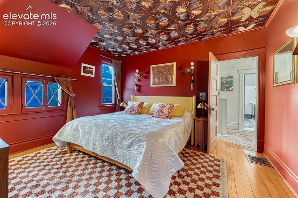 Image 33 of 50: Decorative tin ceiling, multiple windows providing natural light, hardwood 