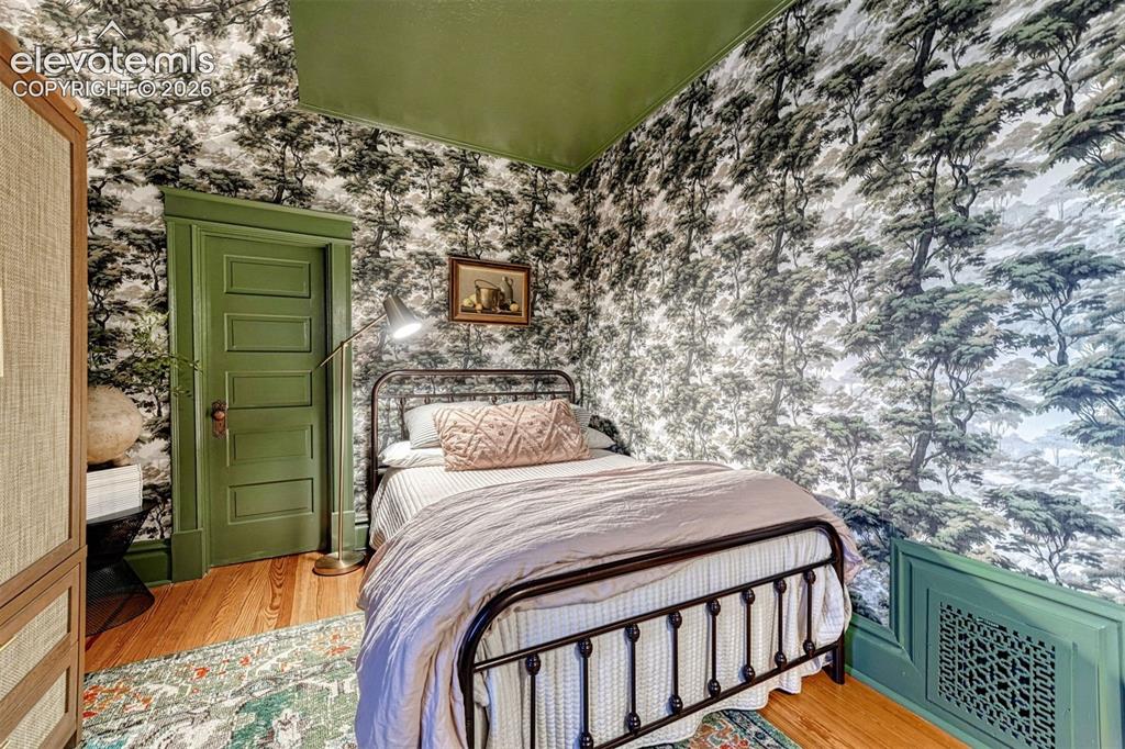 Image 37 of 50: Wood-finish flooring, paneled door with trim, patterned wall covering, gree
