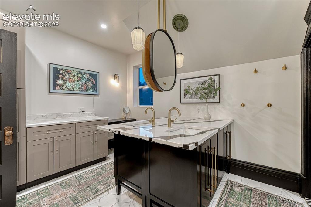 Image 41 of 50: Dual vanity with integrated sinks, white countertops, and brass-tone fixtur