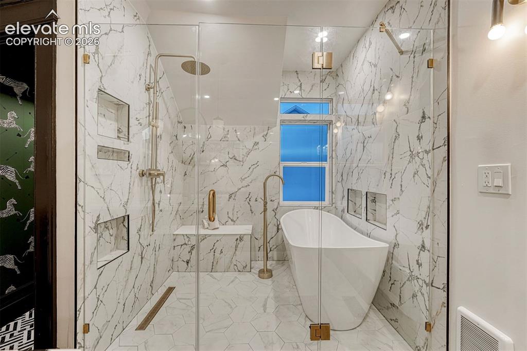 Image 44 of 50: Curbless shower with a linear drain, freestanding soaking tub, tiled shower
