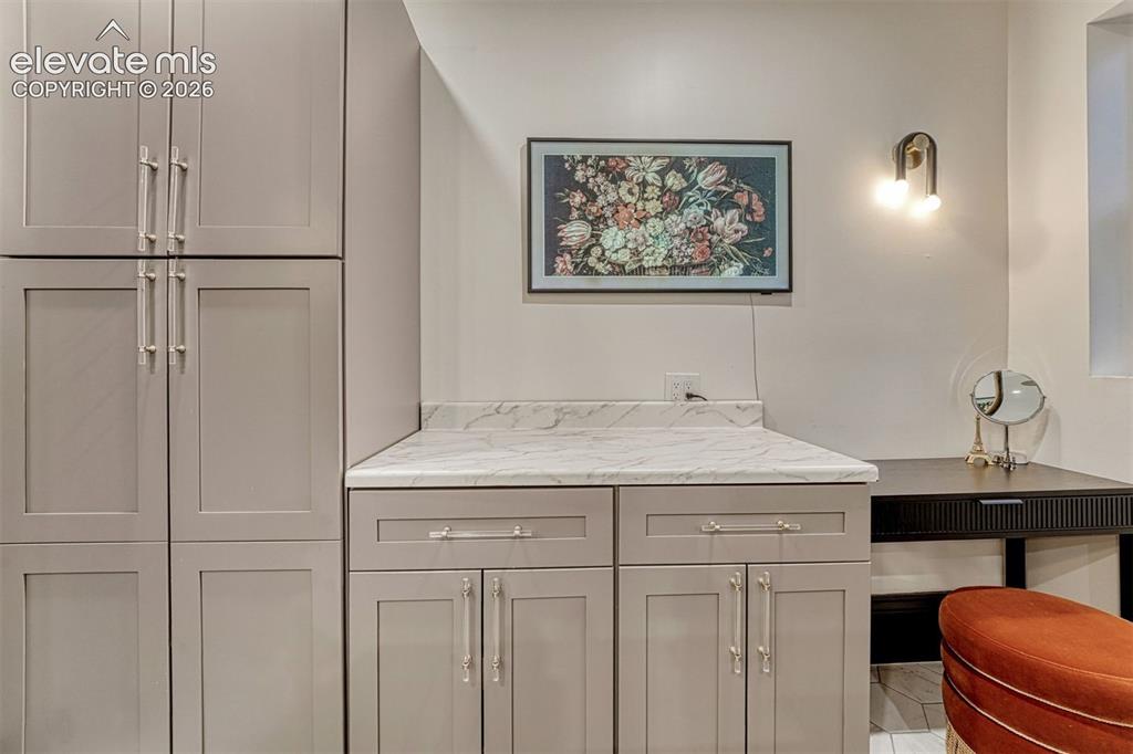 Image 45 of 50: Built-in cabinetry with panel doors and polished nickel hardware, marble-fi
