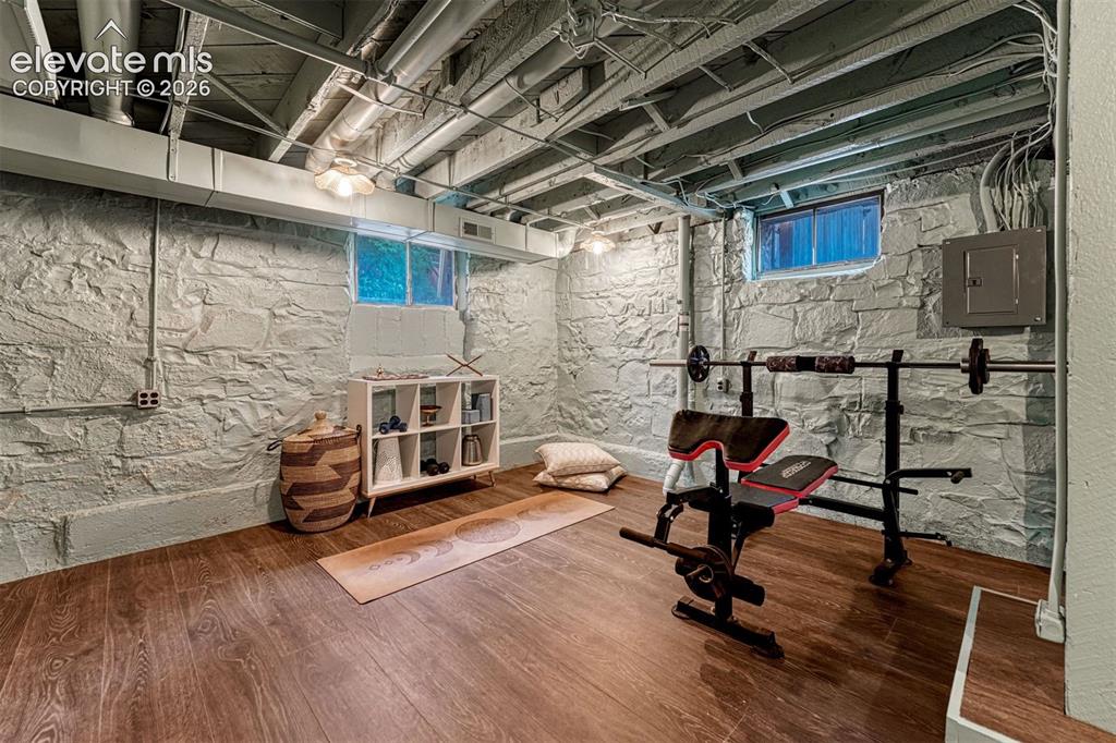 Image 46 of 50: Wood-finish flooring, exposed ceiling beams, painted stone walls, and reces