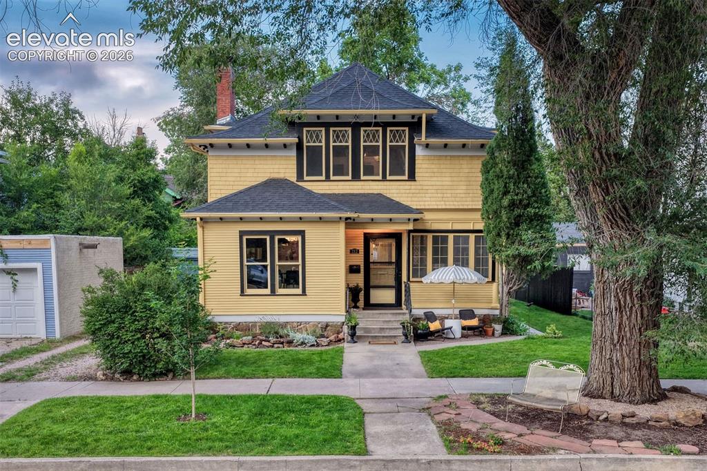 Image 48 of 50: Yellow siding exterior with dark trim accents, gabled roofline, stone found