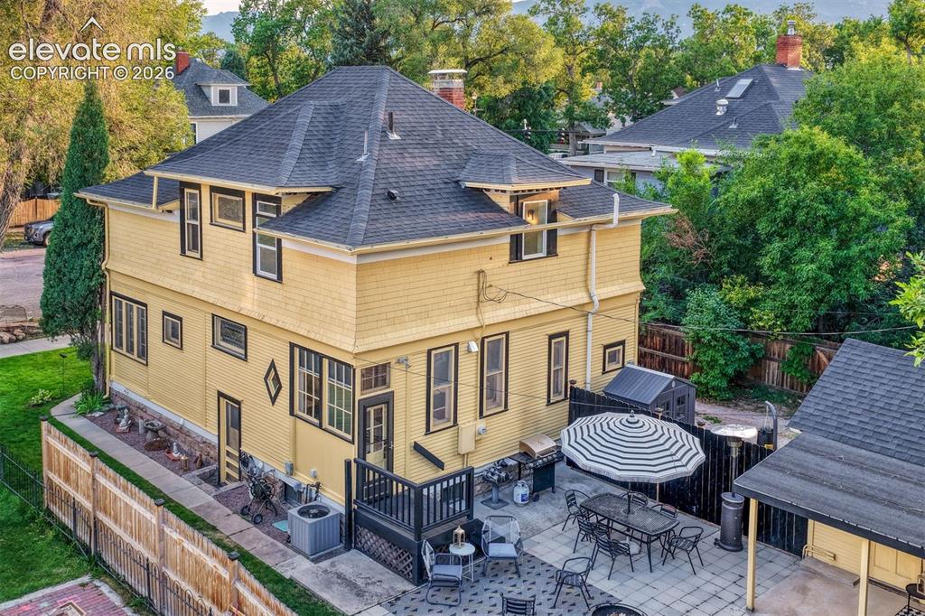Image 49 of 50: Multi-story residence featuring yellow siding, dark trim, and a dark shingl
