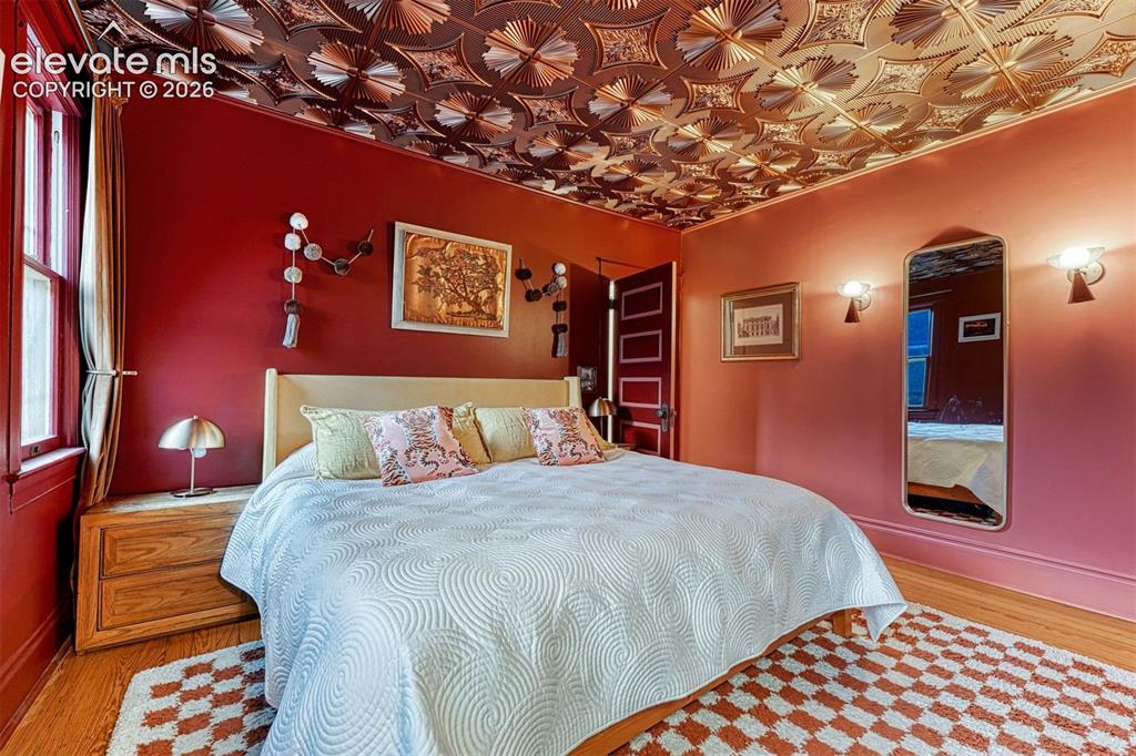 Image 5 of 50: Ornate ceiling panels, wood-finish flooring, built-in sconce lighting, pane