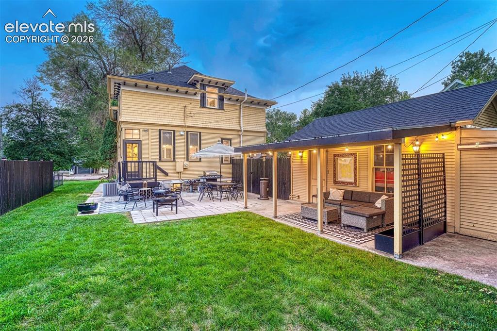 Image 50 of 50: Expansive backyard featuring a manicured lawn, a large paver patio, a cover