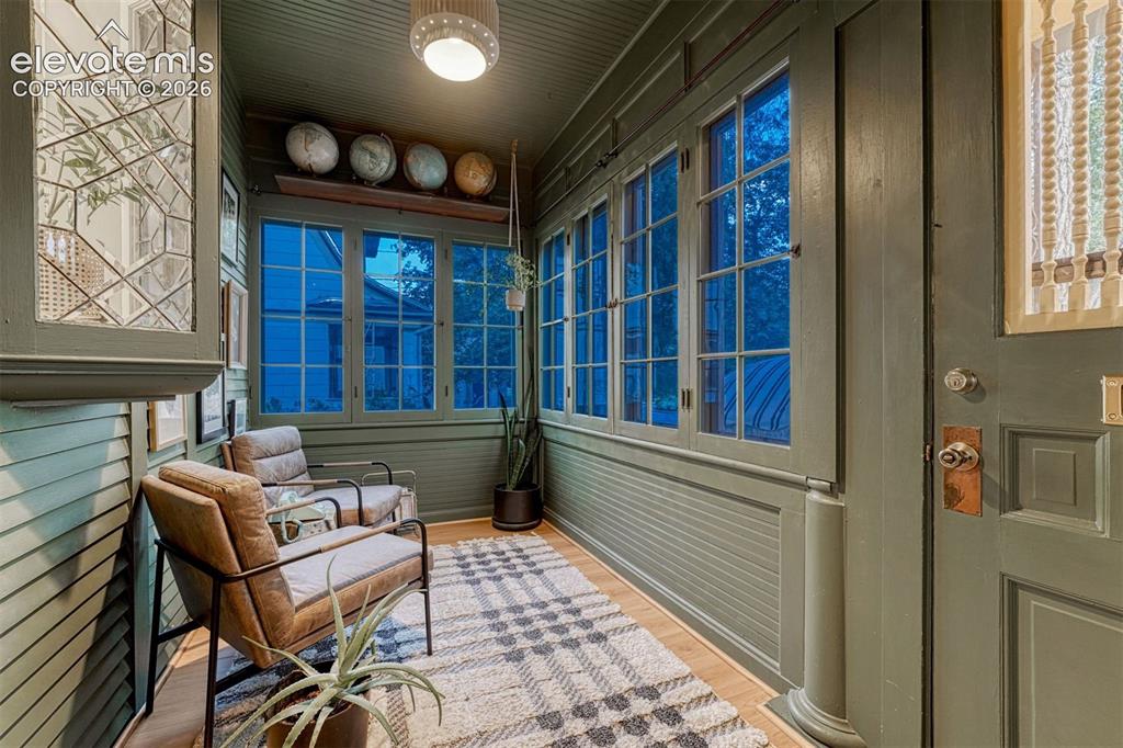 Image 7 of 50: Enclosed entryway featuring extensive window panels, wood-finish flooring, 