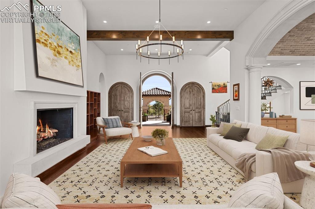 Image 2 of 39: Great room with soaring beamed ceilings, arched entry doors opening to the