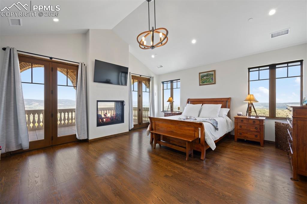 Image 21 of 39: Main-floor primary suite with vaulted ceilings, see-through gas fireplace,