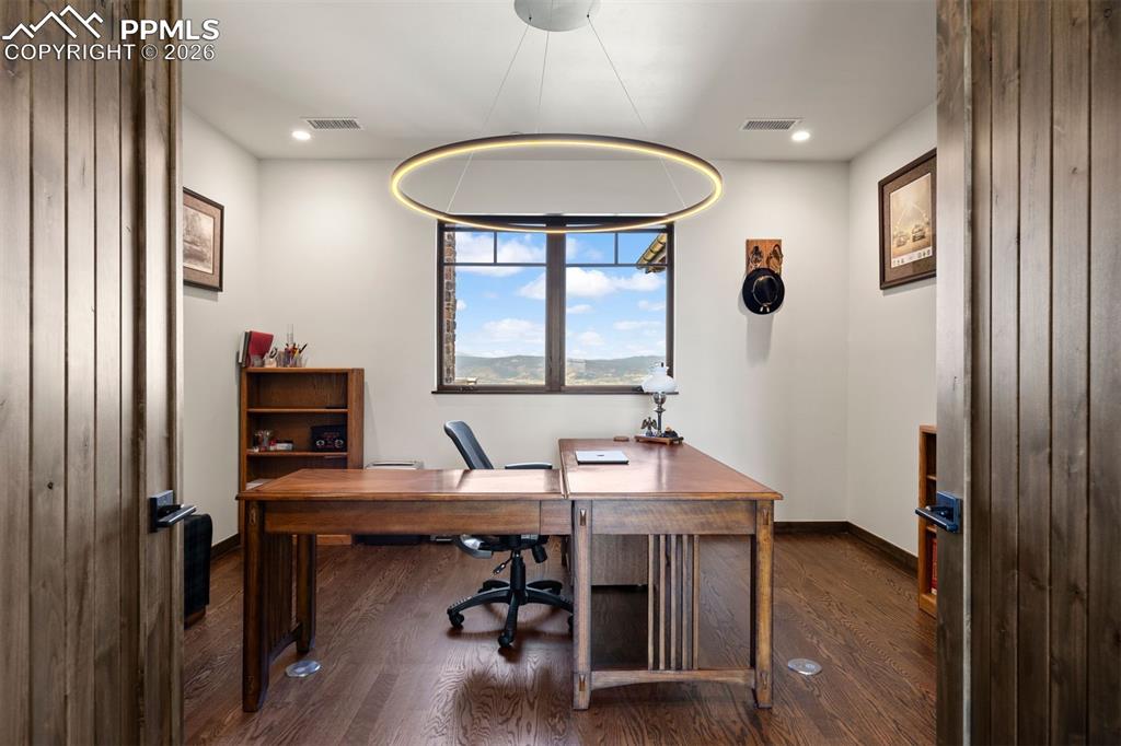 Image 26 of 39: Main-level office with double door entry, built-inbook shelves, and mountai