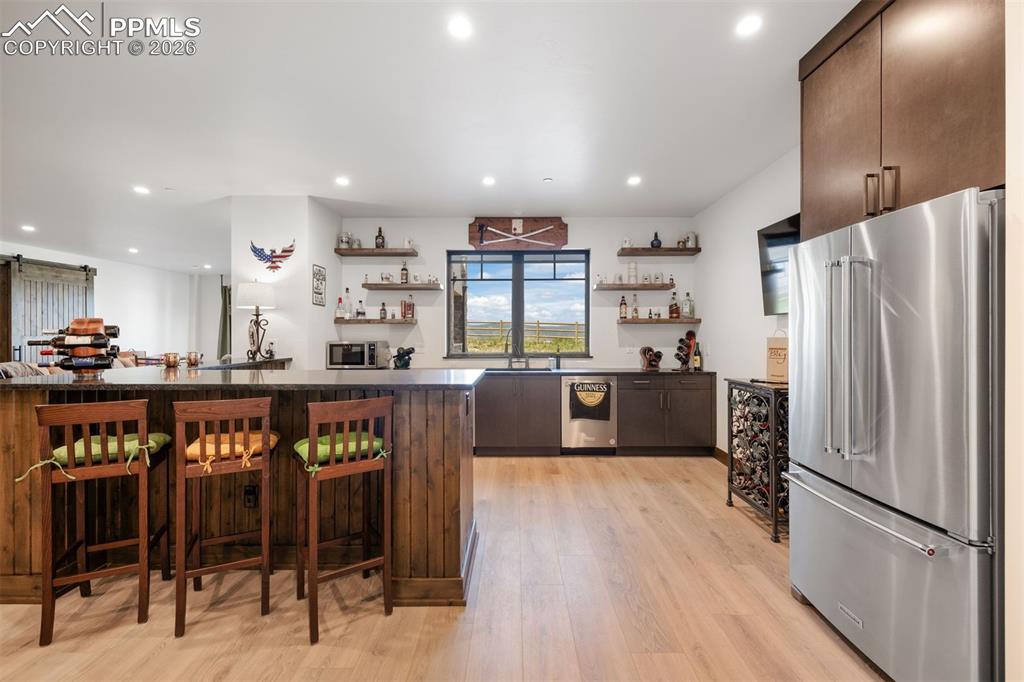 Image 28 of 39: Wet bar with seating, fridge, dishwasher, and ice maker.