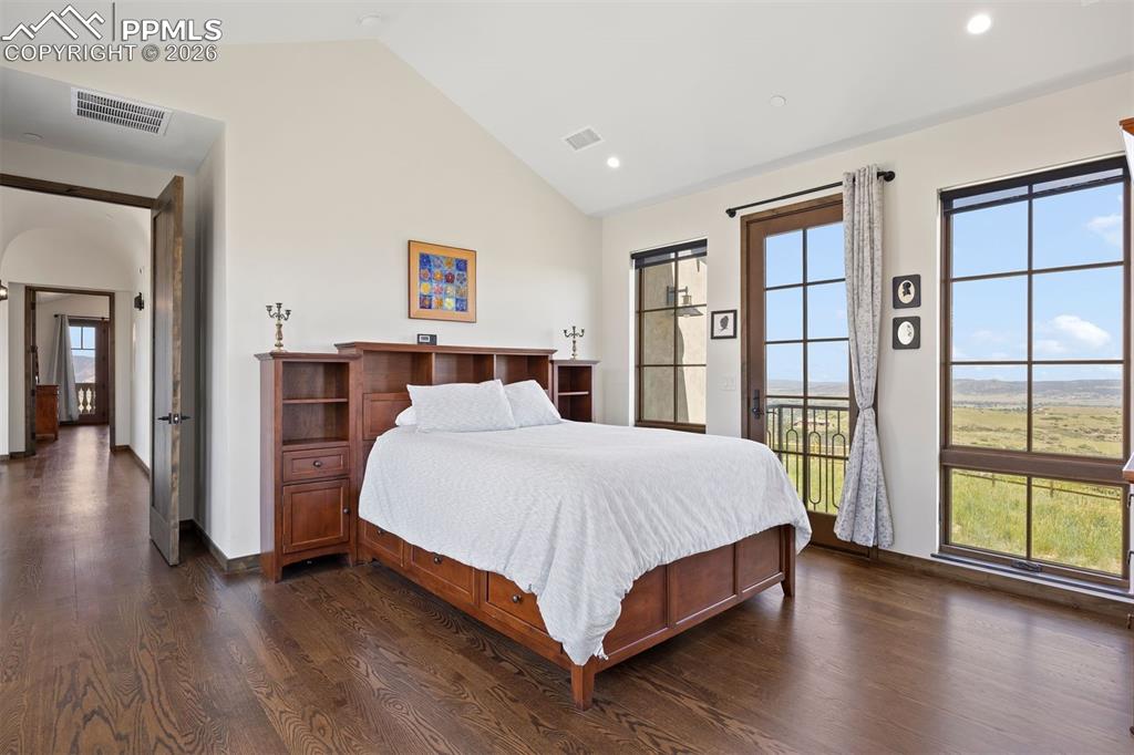Image 30 of 39: Main-level guest suite with Juliet balcony, vaulted ceiling, and private en