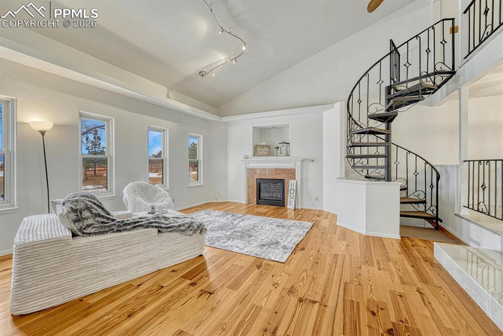 Image 6 of 42: Cozy living room with vaulted ceilings and natural wood floors. View of cus