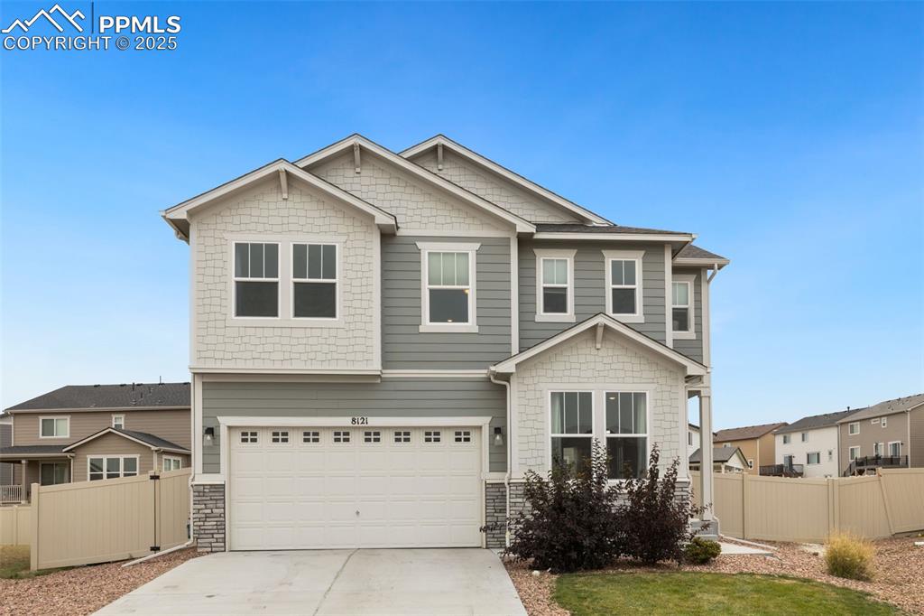 Caption: Craftsman-style house with stone siding, driveway, an attached garage, and a residential view