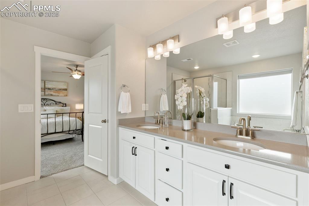 Image 18 of 26: Ensuite bathroom with a stall shower, double vanity, and light tile pattern