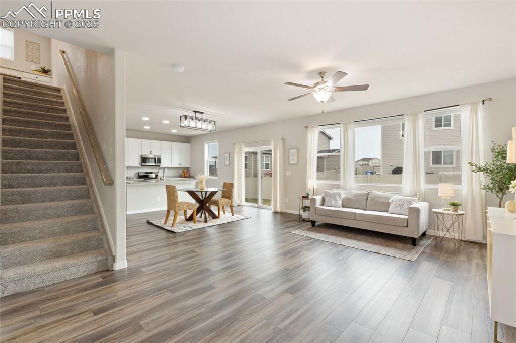Image 4 of 26: Living room with uxury vinyl floors, tons of light, and ceiling fan, stairw