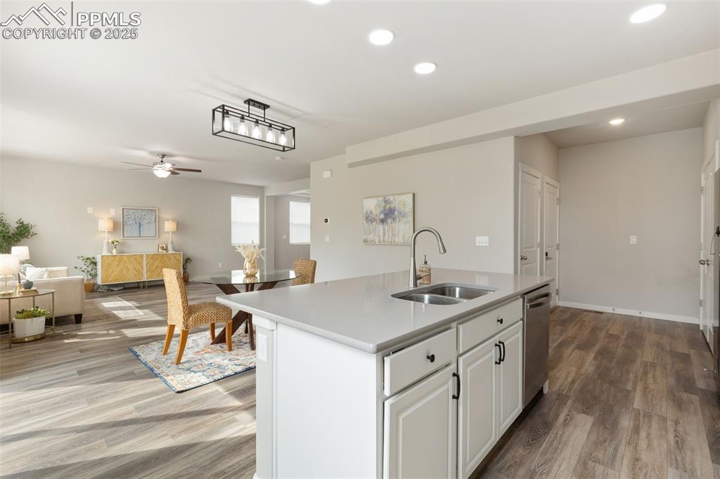 Image 9 of 26: Kitchen with white cabinetry, open floor plan, a ceiling fan, a kitchen isl