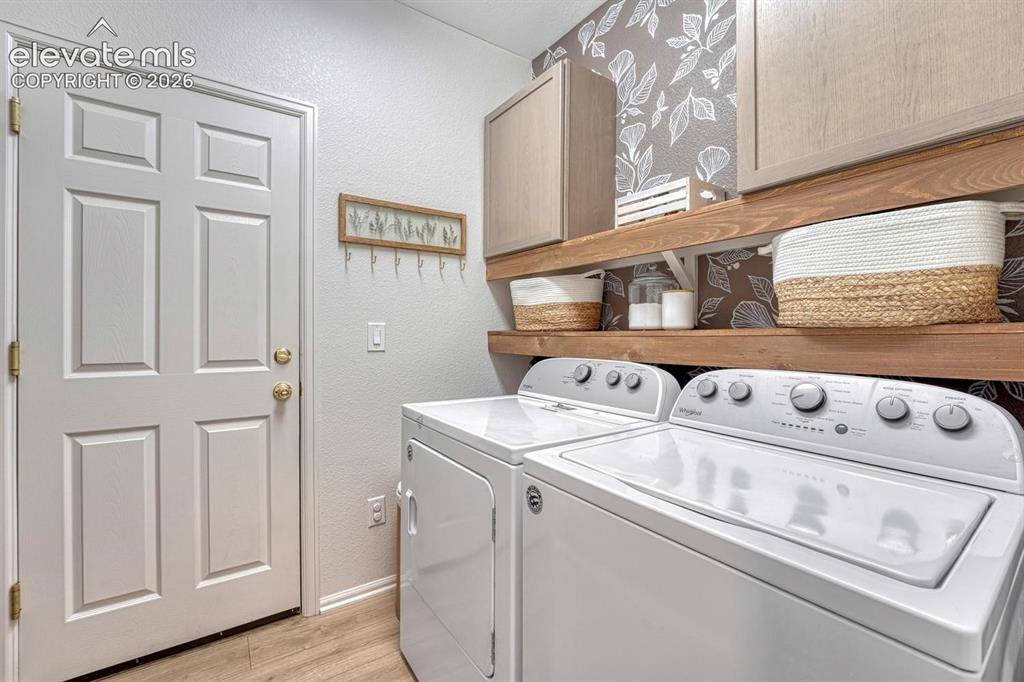 Image 24 of 50: The Laundry Room has garage access and features wood shelving, upper cabine