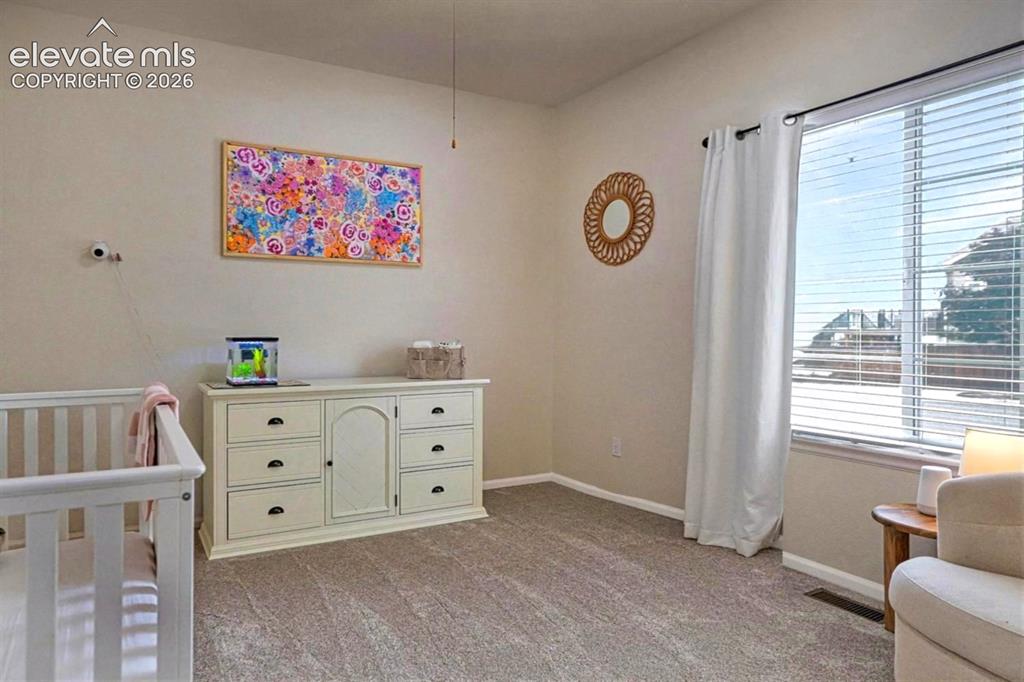 Image 25 of 50: Main Level Bedroom #2 with neutral carpet and lighted ceiling fan.