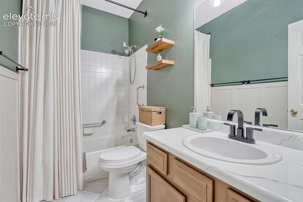 Image 34 of 50: The Primary Bathroom features tile flooring, a vanity, mirror, and tiled tu