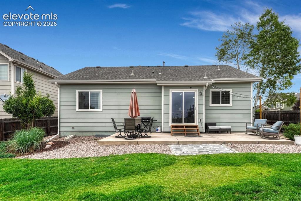 Image 40 of 50: The fenced backyard boasts mature landscaping, lush grass, rock gardens, au