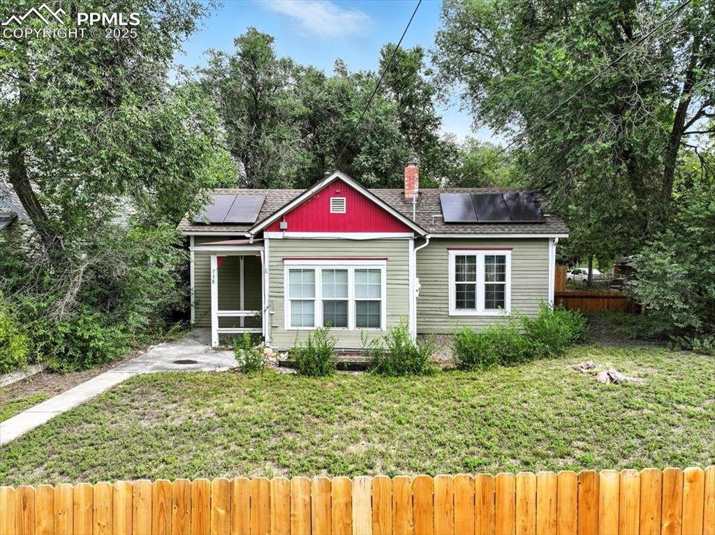 Caption: Bungalow-style home featuring solar panels, a sunroom, and a shingled roof