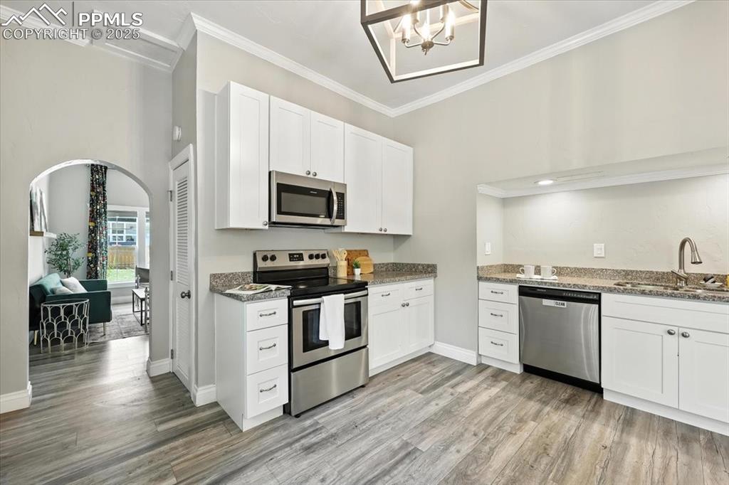 Image 10 of 36: Kitchen featuring stainless steel appliances, arched walkways, crown moldin