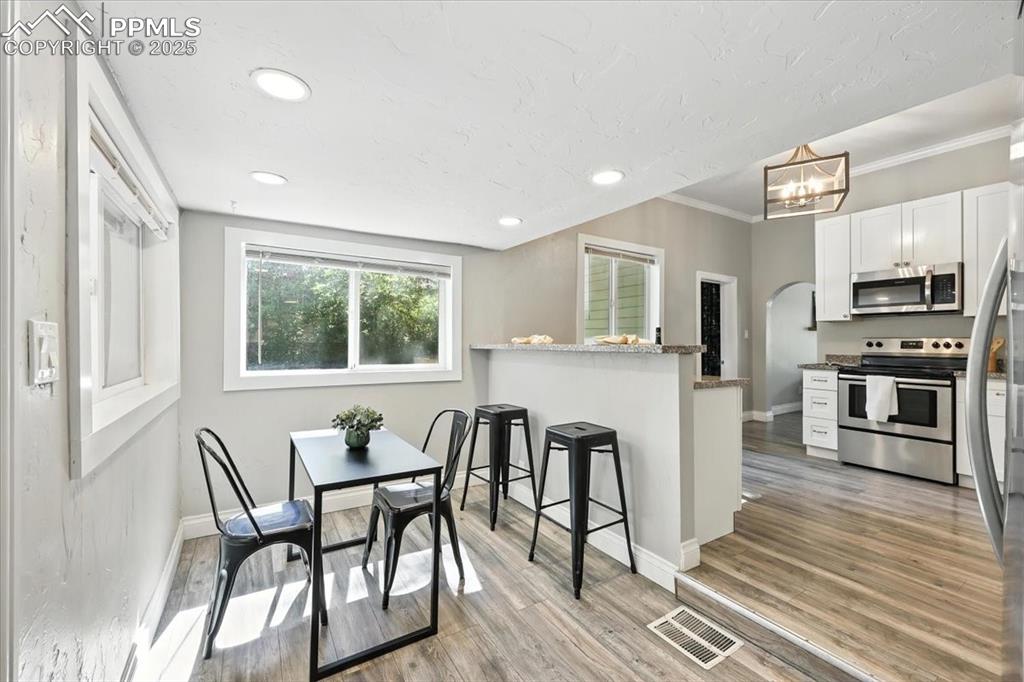Image 11 of 36: Dining area with crown molding, light wood-type flooring, a chandelier, rec