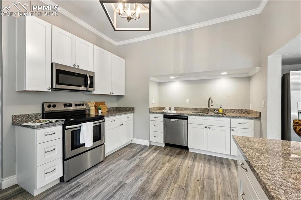 Image 12 of 36: Kitchen with stainless steel appliances, crown molding, light wood finished