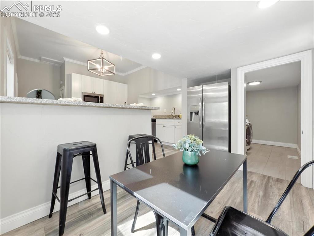 Image 14 of 36: Dining space with light wood-style flooring, crown molding, a chandelier, a